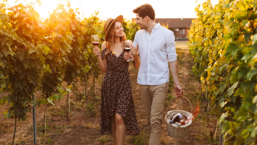 a couple walking with red wine glasses through a vineyard during a Germany wine walk